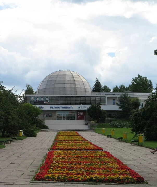 W samym Olsztynie można podziwiać cały kosmos za sprawą Olsztyńskiego Planetarium, które widać na zdjęciu. Budynek ma imponującą kopułę, a przed jego wejściem rozciąga się dywan kwiatowy.