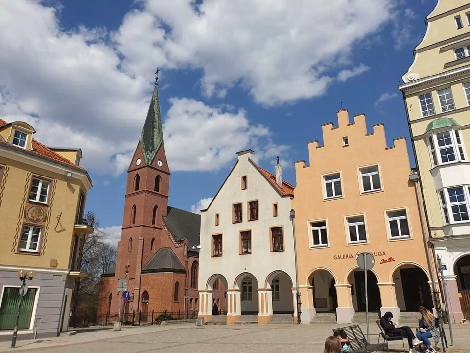 Zdjęcie Starego Miasta w Olsztynie z zabudową kamieniczek oraz kościołem oraz placem.